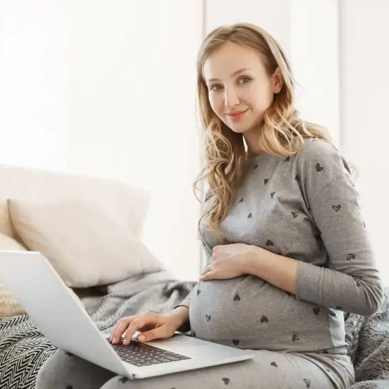 pregnant woman on computer looking at surrogate compensation